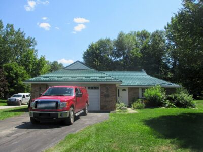 Hy-Grade-Steel-Roofing-System-Metal-Roofing-See-Our-Work-Hunter's-Green-green-yard- brown-red-siding-red-truck-in-driveway