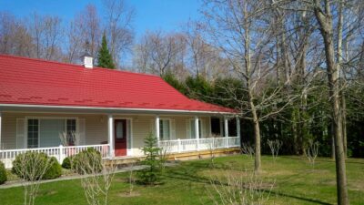 Hy-Grade-Steel-Roofing-System-Metal-Roofing-See-Our-Work-Tile-Red-bungalow-style house-with green grass and blue sky with yellow siding