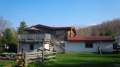 Hy-Grade-Steel-Roofing-System-Metal-Roofing-See-Our-Work-Tile-Red-2 story-style house-with green grass and blue sky with white and wood siding