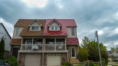 Hy-Grade-Steel-Roofing-System-Metal-Roofing-See-Our-Work-Tile-Red-2-story-style house-with cloudy sky. House is a split house with asphalt on the other side