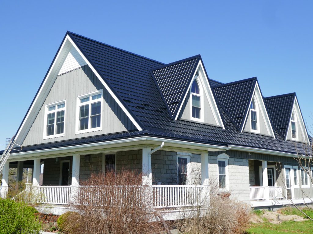 2 story house with a Black Hy-Grade Steel roof in a sunny day with blue sky the siding on the house is white and grey.