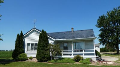 Hy-Grade-Steel-Roofing-System-Metal-Roofing-See-Our-Work-Slate-Grey-large green grass-behind-bungalow-home-with-white siding