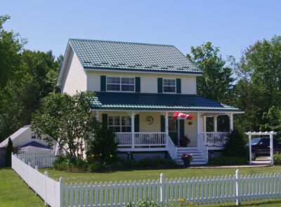 Hy-Grade-Steel-Roofing-System-Metal-Roofing-See-Our-Work-Hunter's-Green-green-yard- white-beige-siding-front-porch-Canadian-flag-white-picket-fence