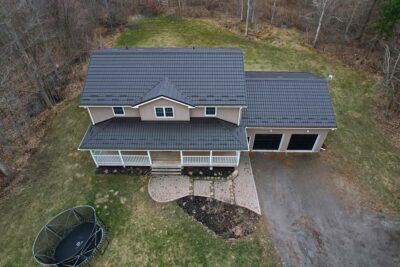 Drone angle with Hy-Grade metal roof in dark brown. Photos taken in spring, ground is still dead from winter. Lots of grass/yard space around the beige bricks