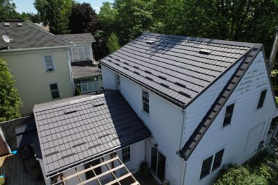 Hy-Grade-Steel-Roofing-System-Metal-Roofing-See-Our-Work-Charcoal-Grey-metal-roof-drone-angle-porch-still-in-progress-in-busy-city