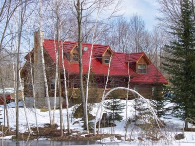 Hy-Grade-Steel-Roofing-System-Metal-Roofing-See-Our-Work-Tile-Red-2-story-log-style house-with snow covering the hill-and-blue-sky