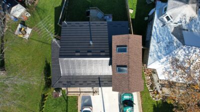 Drone angle bird's eye with Hy-Grade metal roof in dark brown. The top of a hy-grade steel truck is on the right of the driveway.