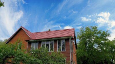 Hy-Grade-Steel-Roofing-System-Metal-Roofing-See-Our-Work-Tile-Red-brown-log-house-with-green-trees-and-blue-sky-upward-angle-with-reddish-orange-tiles