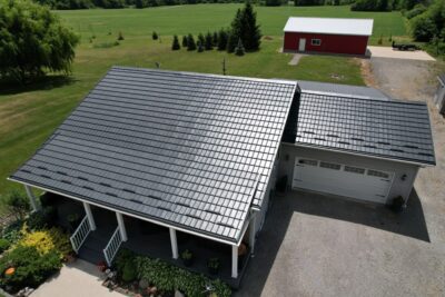 Hy-Grade-Steel-Roofing-System-Metal-Roofing-See-Our-Work-Slate-Grey-large green grass-behind-bungalow-home-with-beige-bricks-angle is from above - drone