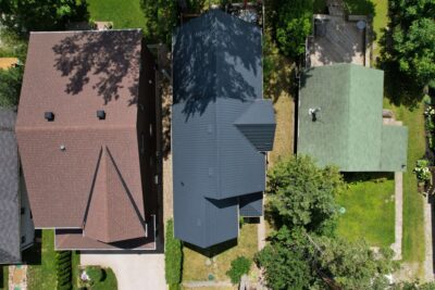Hy-Grade-Steel-Roofing-System-Metal-Roofing-See-Our-Work-Slate-Grey-shows 3 homes from above, the steel roof is in the middle-angle is from above - drone