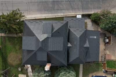 A Hy-Grade steel roof from a bird's eye view can be seen with a red brick chimney poking out in the bottom of the image.