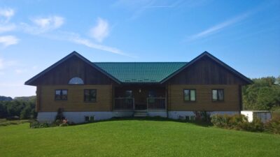 Hy-Grade-Steel-Roofing-System-Metal-Roofing-See-Our-Work-Hunter's-Green-green-yard- brown-wood-siding-back-porch