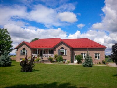 Hy-Grade-Steel-Roofing-System-Metal-Roofing-See-Our-Work-Tile-Red-bungalow-style house-with green grass and blue sky with red brick siding