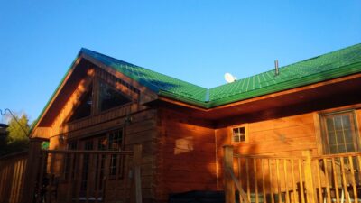 Hy-Grade-Steel-Roofing-System-Metal-Roofing-See-Our-Work-Hunter's-Green-green-yard- brown-wood-orange-siding-up-close-porch