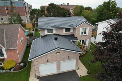 Hy-Grade-Steel-Roofing-System-Metal-Roofing-See-Our-Work-Slate-Grey-large green grass-behind-bungalow-home-with-beige-bricks-angle is from above - drone