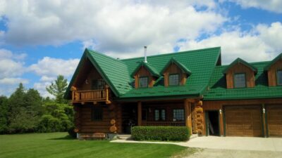 Hy-Grade-Steel-Roofing-System-Metal-Roofing-See-Our-Work-Hunter's-Green-green-yard- brown-log-siding-front-porch-bushes