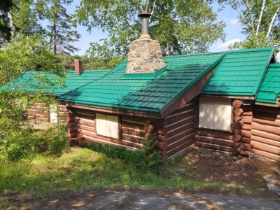Hy-Grade-Steel-Roofing-System-Metal-Roofing-See-Our-Work-Hunter's-Green-green-yard- brown log-siding-chimney in middle-stone