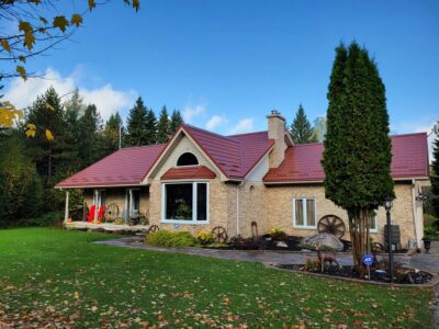 Hy-Grade-Steel-Roofing-System-Metal-Roofing-See-Our-Work-Tile-Red-bungalow-style house-with green grass and blue sky with yellow brick siding