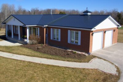 Hy-Grade-Steel-Roofing-System-Metal-Roofing-See-Our-Work-Slate-Grey-large green grass-behind-bungalow-home-with-beige-bricks-angle is from above - drone